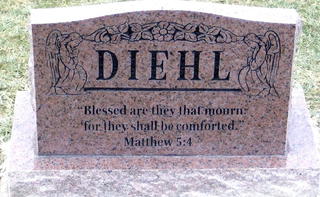 Rose granite upright with two carved kneeling angels and a scripture inscription
