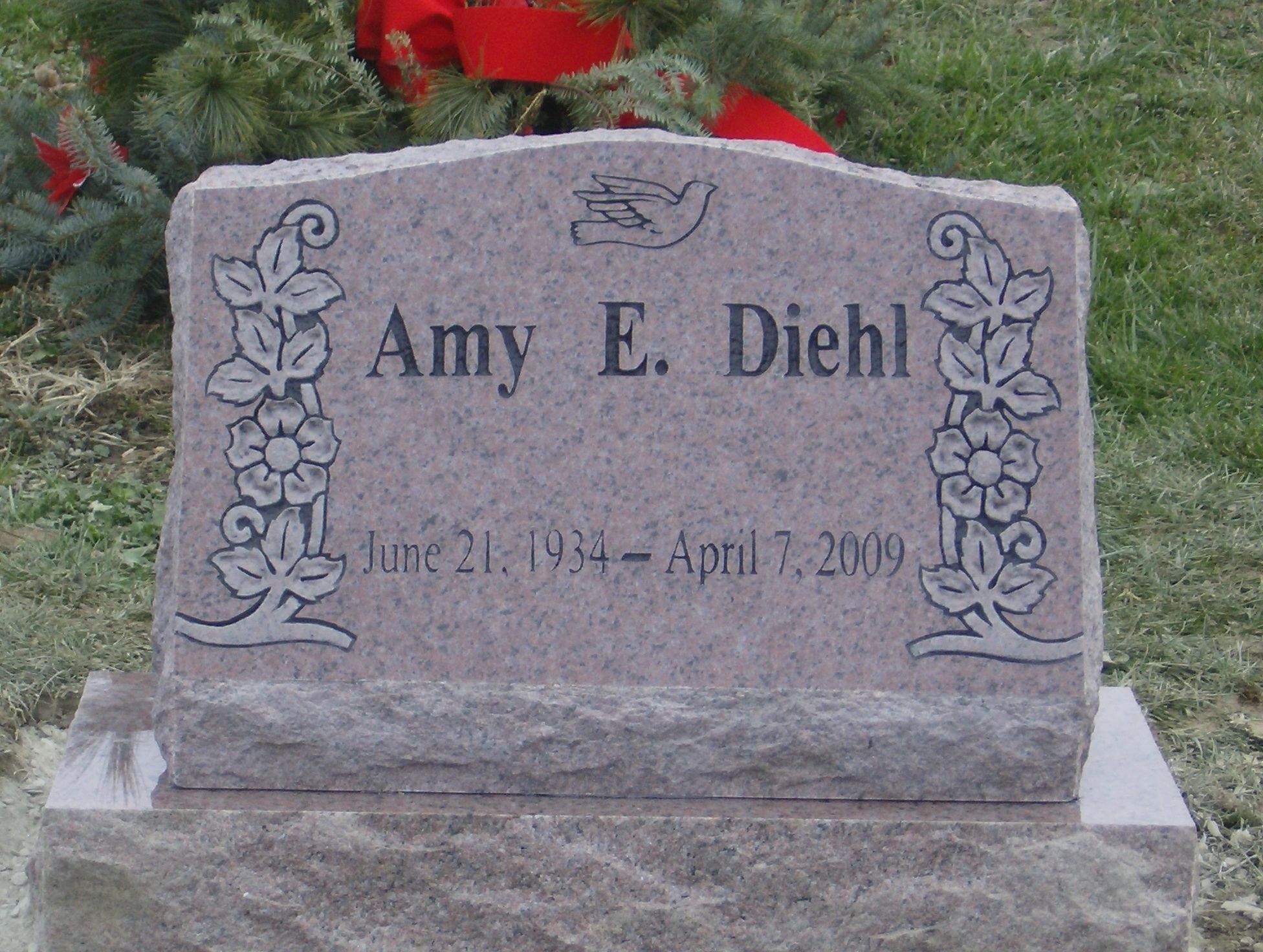 Pink granite slant marker with carved flowers and a dove