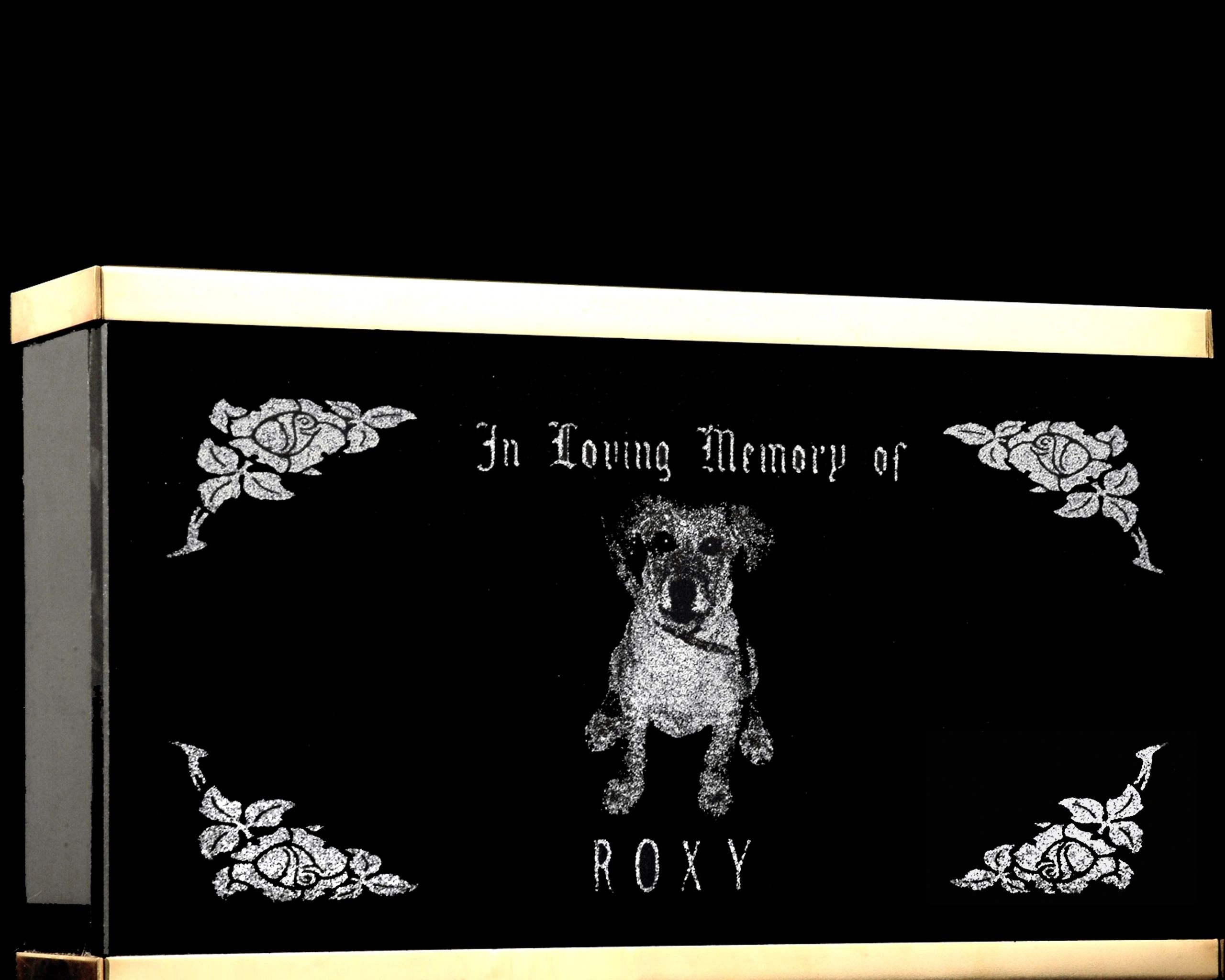 A black granite memorial box with brass trim and an etched portrait of a dog