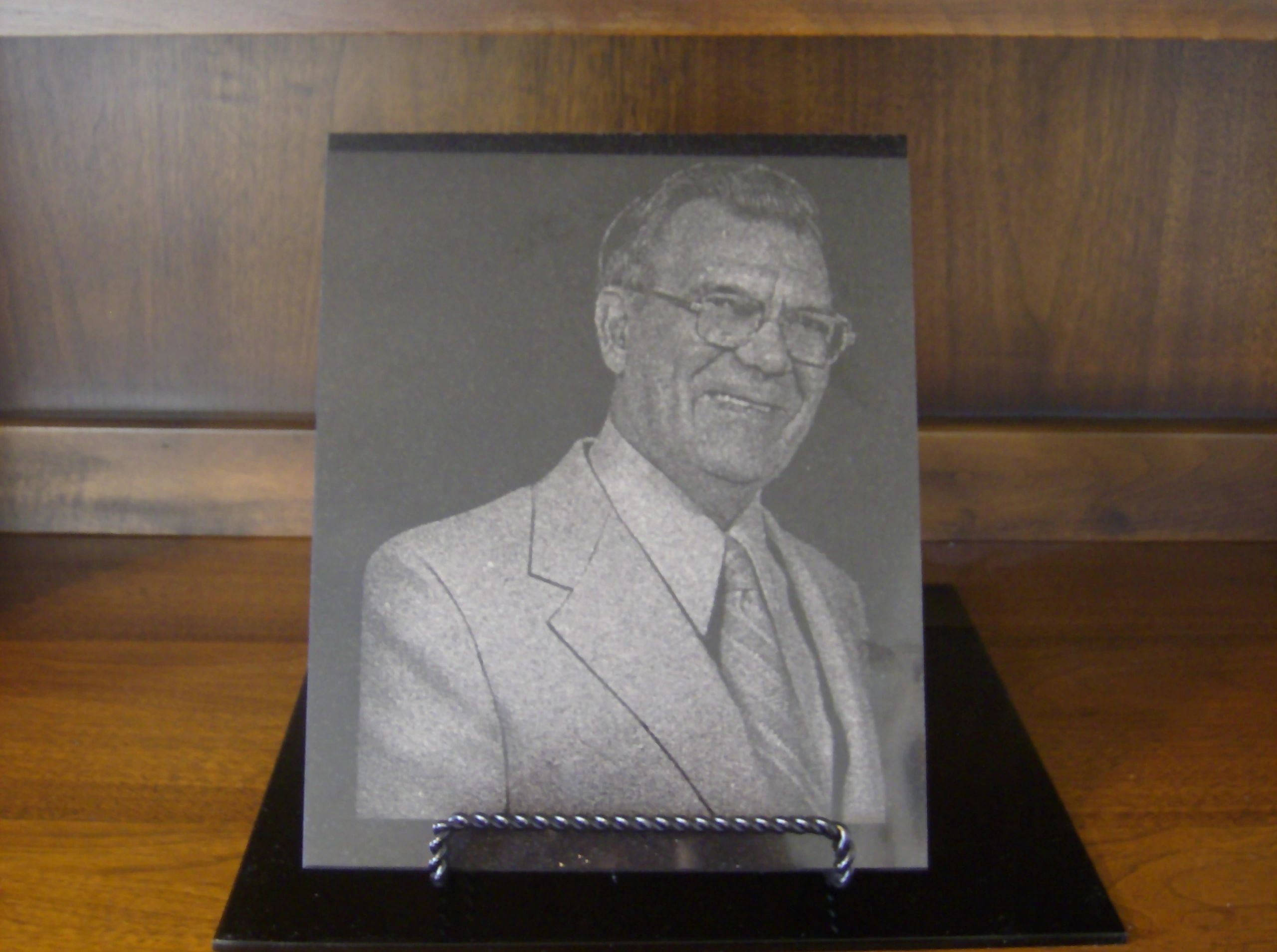 An etched portrait of a man on granite, standing on a display easel