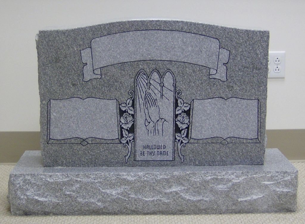 Grey upright with carved open books, praying hands and a carved inscription