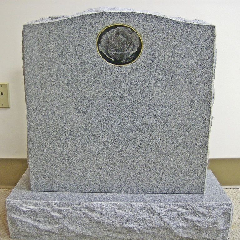 Grey upright with a carved rose relief insert set in a bronze ring